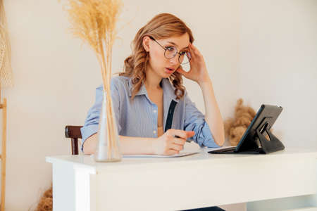 A fairly young business woman uses a modern digital tablet in the office, working in the home...