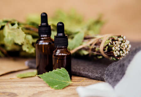 Cosmetics for spa treatments and baths on a wooden table with a birch broom. Essential oils and accessories for the bath.の写真素材
