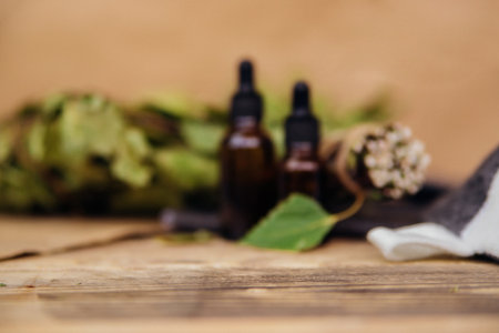 Cosmetics for spa treatments and baths on a wooden table with a birch broom. Essential oils and bath accessories. Blurred background.の写真素材