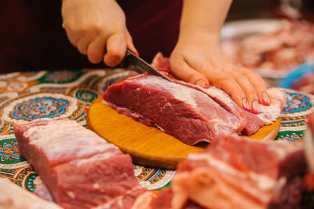 Women's hands cut raw meat with a knife. fresh beef. Preparation for cooking. dietary meat.