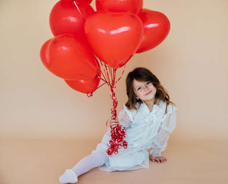 Cute little girl with heart shaped balloons on Valentine's day. family, love. gifts for the holiday. happy birthday baby.の写真素材