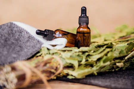 Cosmetics for spa treatments and baths on a wooden table with a birch broom. Essential oils and accessories for the bath.の写真素材
