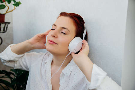 A beautiful young woman listens to music with headphones. The concept of people's lifestyle. Enjoying the melody, closed eyes.の写真素材
