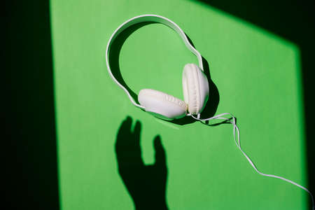 Headphones on a green background. A musical concert. view from above. Fashionable colorful, abstract photography. The shadow of a woman's hand.の写真素材