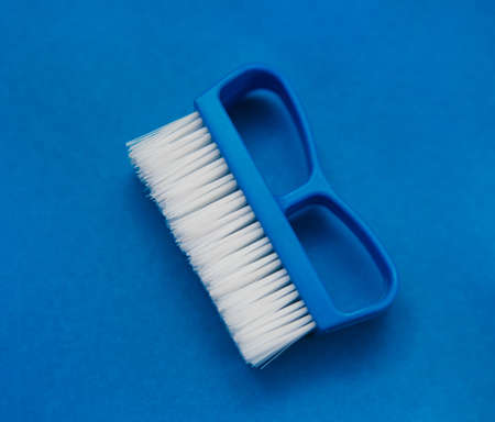 Close-up cleaning brush on a blue background. A brush with a white pile and a blue handle. Convenient equipment for cleaning the house.の写真素材