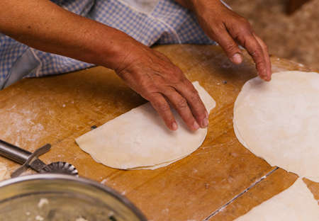 Women's hands in the process of cooking kutaba or chebureks, minced meat and onions in the dough.Cottage cheese and onion in the dough. Azerbaijani, Tatar, Caucasian, Greek cuisine.の写真素材