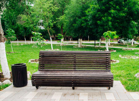 A bench in a square-shaped public park. wooden panels. A place of rest and reflection.