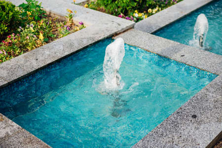 A small fountain in the city park. splashing water, bright sunlight. Fresh and cool water on a...