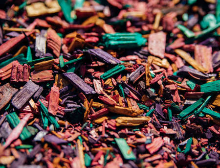 Textured background of decorative colored sawdust for finishing flower beds. Green, burgundy, yellow, red and purple sawdust. The texture of small colored wood chips.の写真素材