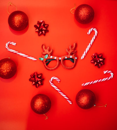 Christmas fancy dress glasses with deer antlers, balloons, lollipops on a red background. The concept of a Christmas party. A fun holiday. Decoration for children and adults.の写真素材