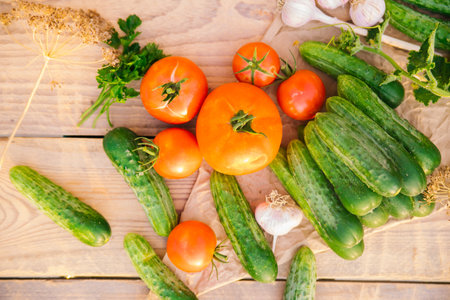 Fresh vegetables on a wooden background. The concept of healthy eating. Cucumbers, tomatoes, garlic, dill. Top view.の写真素材