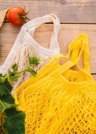 Reusable shopping bag, string bag made of recycled materials, on a wooden table among fresh vegetables. No plastic. Eco-friendly lifestyle.の写真素材