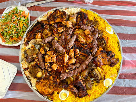 Chicken Kabsa or chicken and meat biryani on a wooden background. Kabsa is a traditional Arabic...