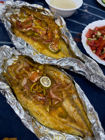 Grilled whole fish, potatoes, lemon, and garlicの写真素材