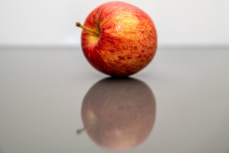 Red apple on a glass table with reflection. Shallow depth of fieldの写真素材