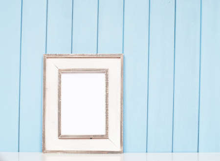 Old vintage picture frame on the bookshelf on blue wooden backgroundの写真素材