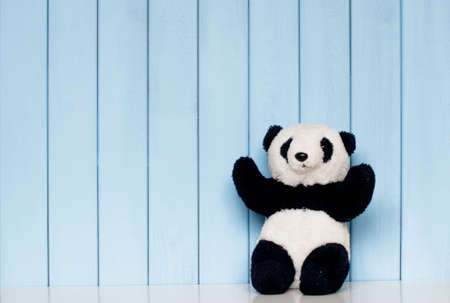 old vintage panda soft toy on the bookshelf in the children's room on the blue wooden backgroundの写真素材