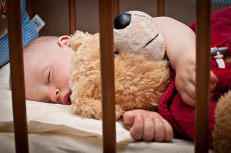 little baby is sleeping in his bed with his toyの写真素材