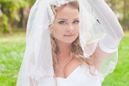 Beautiful bride is sitting on the grass in the gardenの写真素材