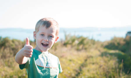 Cute cheerful little boy shows like sign