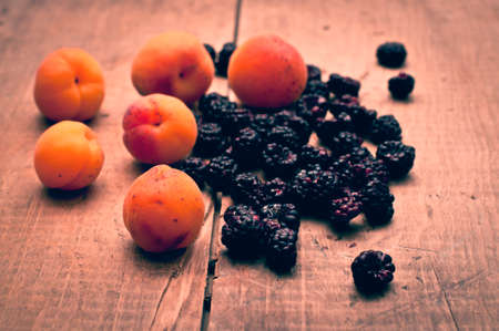 Fresh apricots and blackberries on wooden backgroundの写真素材