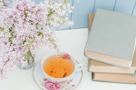 vintage books, gentle bunch of lilac and china teacup on the table on blue wooden backgroundの写真素材