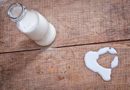 milk in glass bottle and heart shaped symbol on wooden tableの写真素材
