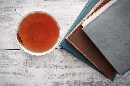 Old books and cup of teaon wooden tableの写真素材