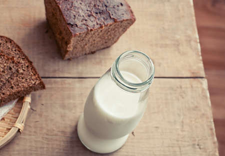 Bottle of milk and slices of rye brown bread on rustic wooden tableの写真素材