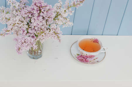 Gentle bunch of lilac and china teacup on the table on blue wooden backgroundの写真素材