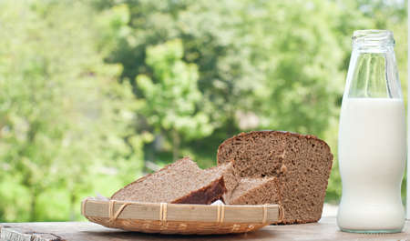 Bottle of milk and slices of rye brown bread on rustic wooden tableの写真素材