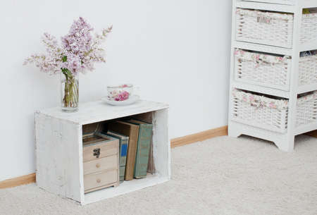 gentle bunch of lilac and china teacup on vintage shabby nightstand with wooden box and ancient books insideの写真素材