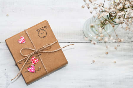 Gift package wrapped with paper, rope with hearts and dry bouquet on vintage wooden backgroundの写真素材