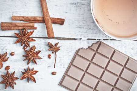 cinnamon stick, star anise, bar of chocolate and cup of tea on wooden tableの写真素材
