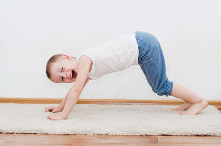 Happy kid is playing on white carpet in his roomの写真素材