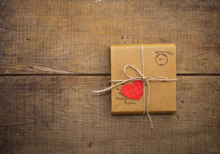 Gift package wrapped with paper and rope with heart on vintage wooden backgroundの写真素材