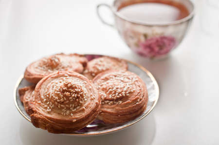 Puff cookies with sesame seeds on plate and english teaの写真素材