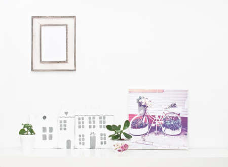 Empty picture frame, bicycle on picture and small houses on white wallの写真素材