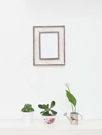 Empty picture frame and flowers on white wallの写真素材