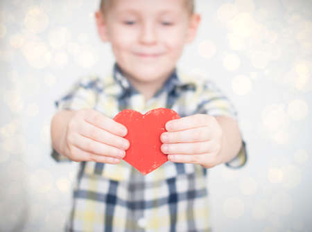little kid is giving a red heart to his momの写真素材