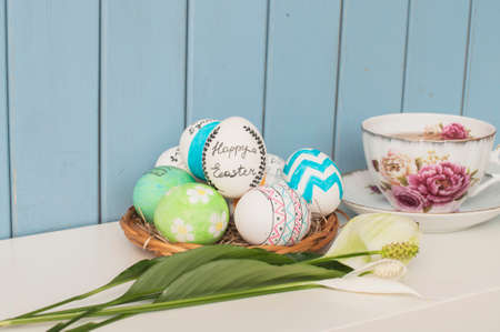 easter eggs, english tea and flowers  on the blue backgroundの写真素材