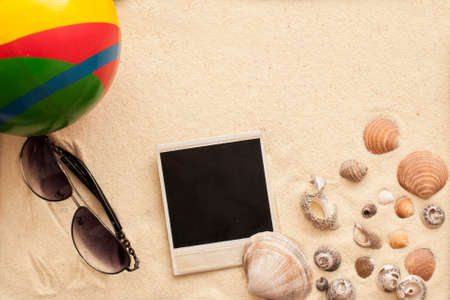 sea shells, ball, sunglasses and instant picture on sandの写真素材