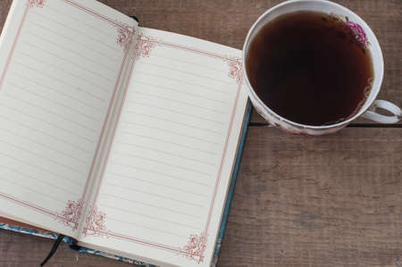 still life with coffee mug and blank notebook on vintage wooden tableの写真素材