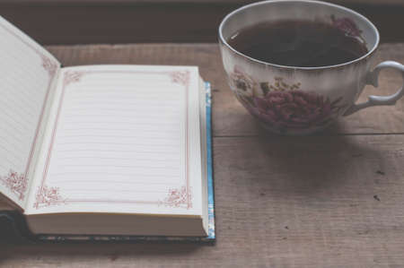 still life with coffee mug and blank notebook on vintage wooden tableの写真素材