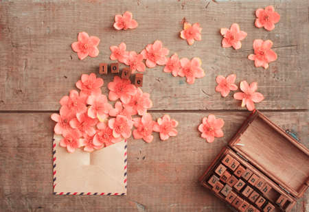 word love by wooden stamps with pink gentle flowers on vintage table in the morningの写真素材
