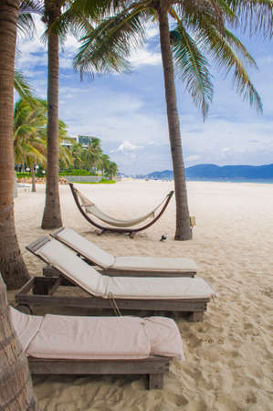 Sunbeds, hammock, white sand, blue sea and palms in the My Khe beach, Danang, Vietnamの写真素材