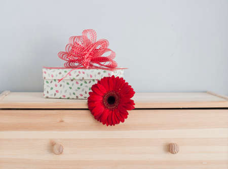 a gift box with red ribbon and a flowerの写真素材