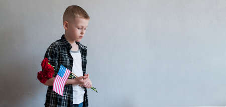 Little boy celebrating Memorial day with flowers and American flagの写真素材