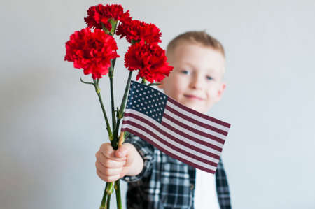 Proud  cheerful boy celebrates Memorial day with flowers and American flagの写真素材