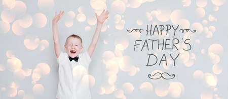 Happy cheerful kid with hands up celebrates father's dayの写真素材